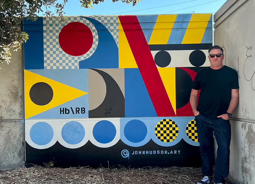 John Hudson in front of his mural